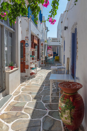 Cycladitic alley with a narrow street and  an exterior  of a traditional  whitewashed cafe with chairs and tables  in Chora kythnos,cyclades, Greece.の写真素材