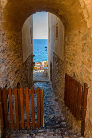 Traditional cafe exterior in the fortified medieval  castle of Monemvasia. Iron tables and wooden chairs  with the view of the  aegean sea in the background.のeditorial素材