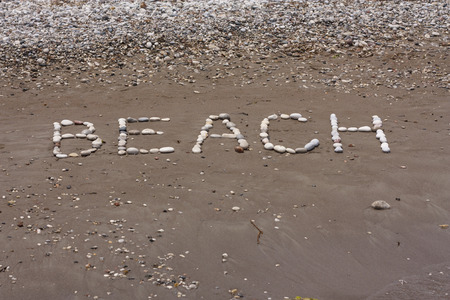 Stones sea in wet sand of beach in sunny day photoの写真素材