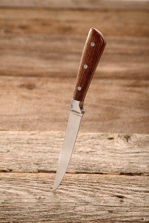 Kitchen knife stuck in the wooden table