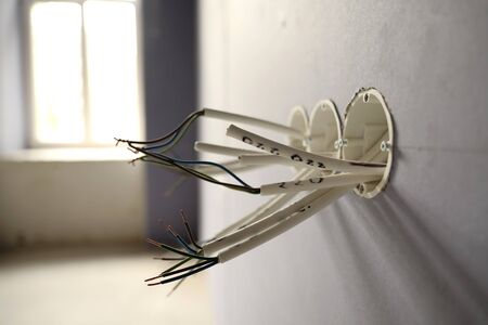 Several exposed copper wires protruding from a wall