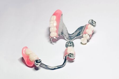 a set of removable clasp prostheses with supporting metal-ceramic and metal crowns on the upper and lower jaws on an isolated backgroundの写真素材