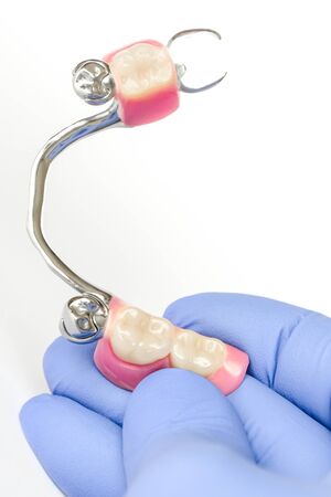 clasp denture on the lower jaw with supporting crowns in the hands of the dentistの写真素材