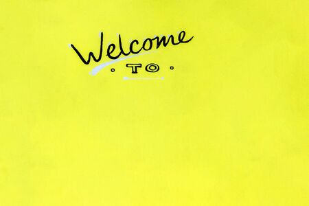 the inscription welcome to is drawn by hand on a yellow wooden board. copy space. reception signの写真素材