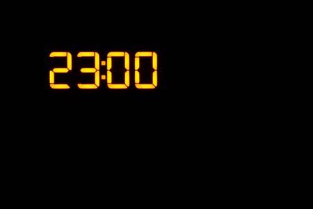 electronic clock showing the time 23:00 on the display orange LEDs on a black background. copy spaceの写真素材