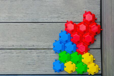 game puzzle of multi-colored hexagons assembled on a wooden gray background. green blue red yellow