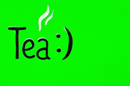 Tea party card design. inscription tea with a smiley in black paint on a green wooden board. copy spaceの写真素材