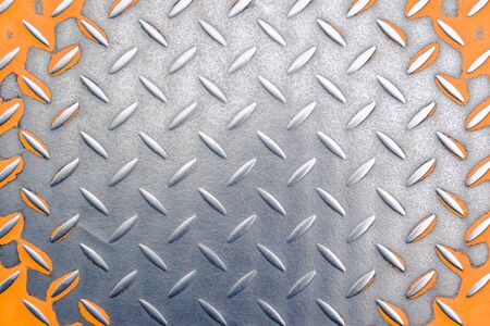 old metal floor with a diamond pattern. scratched and polished metal. orange paint on the sides. metal backgroundの写真素材