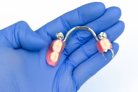 removable prosthetics concept. prosthetics with false teeth. denture in the hand of a dentist. arch...