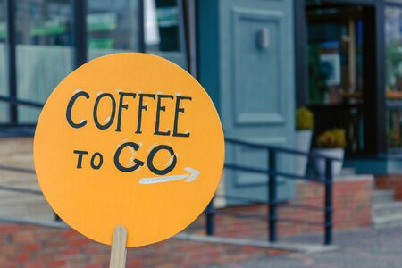inscription coffee to go on an orange wooden plank. coffee shop, cafe advertisement. takeaway coffeeの写真素材