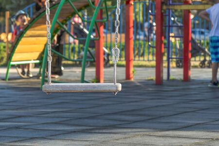 empty swing at the playground. The concept of childhood and fun. wooden plaque on a metal chainの写真素材