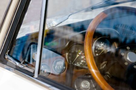 view of the steering wheel and dashboard of a car of the 70s. on glass the reflection of the mirror in sunny weatherの写真素材