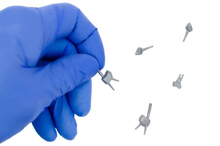 cast dental pins with dentist hand in glove isolated on white background. tooth pinning conceptの写真素材