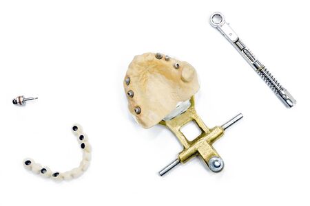 white ceramic teeth with dental implants on a white background. torque wrench and dental screwdriver. concept of dental implantation and orthopedic dentistry on implants. backgroundの写真素材