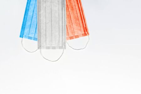 three medical masks of blue, white and red are located at the top on a light background. flag of france. France virus outbreak concept. coronavirus in france. copy space. flat layの写真素材