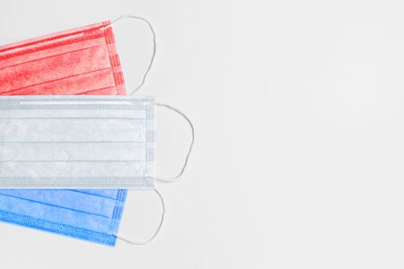 on the left are 3 medical masks of red, white and blue colors on a light background. masks are collected in the flag of the Netherlands. medicine concept in the Netherlands. coronavirus outbreak in the Netherlands. Pandemic in the Netherlands. copy space. flat layの写真素材
