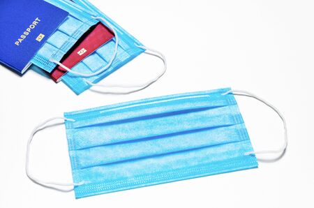 blue medical facial mask lies on a white background. in the background are two foreign passports of blue and red color with nested masks. world quarantine concept. coronavirus outbreak news backgroundの写真素材