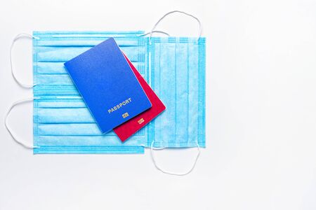 two foreign passports of blue and red colors are on medical masks on a light background. world quarantine concept. Flat Lay. Copy spaceの写真素材
