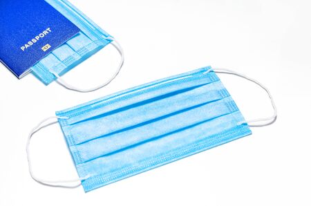 The medical facial mask lies on a white background, in the upper left corner there is a blue foreign passport with a mask. concept of world quarantine and travel ban. coronavirus outbreak. isolated on whiteの写真素材