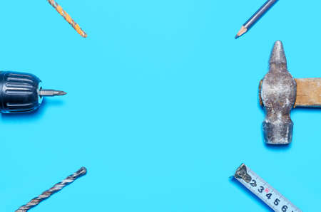 screwdriver, tape measure, hammer, pencil and drill on a blue background. copy space. renovation conceptの写真素材