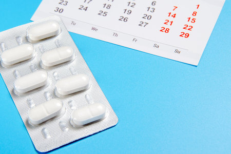 blister of pills with calendar on blue background. doctor treatment concept. copy spaceの写真素材