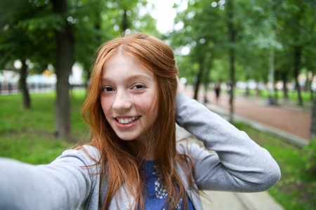 Girl walks in the park and makes selfie, happy.の写真素材