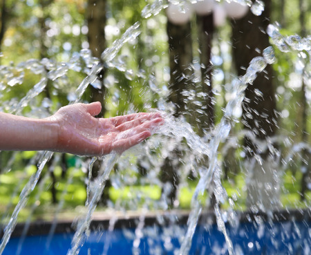 Hand touches clean and fresh water from the fountain.の写真素材