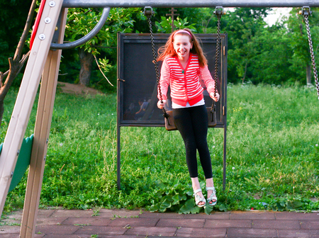 Happy little girl on a swing outdoors.の写真素材