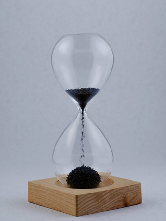 Hourglass on a wooden stand. Very small metal balls are used as sand.