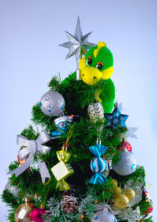 Toy dragon on top of a decorated artificial Christmas treeの写真素材