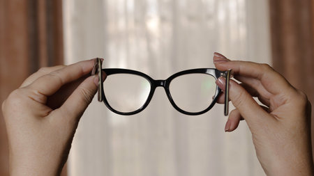 Examining the cleanliness of glasses in a black plastic frameの写真素材