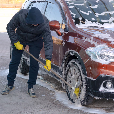 A man at a car wash cleans the wheel of a carの写真素材