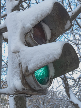 Old pedestrian traffic light in the snow. Permitting movement - green lightの写真素材