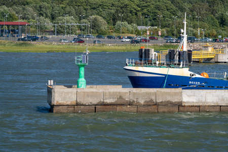 Estonia, Rohukula - 2021.07.20 - Port of Rohukula. View of Rohukula pier and harbor lighthouseA blue ship moored at the pier with a green lighthouseのeditorial素材