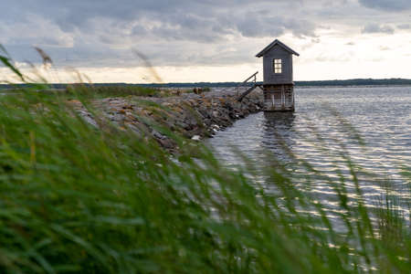 sea pier with a small wooden house next to itEstonia, on the island of Hiiumaa, next to a rocky pier, there is a small wooden house rising above the waterの写真素材