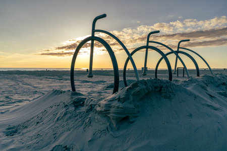 sunset on a sandy sea beach with decorative snowmobiles in the foreground.

Beach stands in the form of old-fashioned bicycles are embedded in the sand of the beach. In the background is a sunset where the sun touches the sea horizonの写真素材