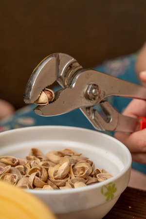 plumbing wrenches are used instead of nutcrackers to crack nut shells. pistachio shells visible in the cup.の写真素材
