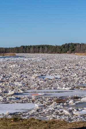 the entire width of the river is filled with ice floes and ice ravines flowing into the sea. A hole will appear in the ice piece next to an orange mark.の写真素材