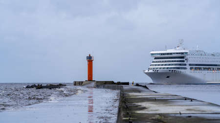 The cruise ship approaches the sea pier and the lighthouse at its enda pier with a lighthouse and a cruise ship approaching the lighthouse to enter the portの写真素材