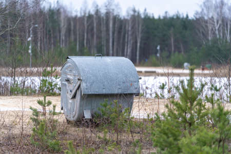 the waste container is located at the water tank on the shore between small trees and grass.Winter morning by a frozen lake with a waste container in the foregroundの写真素材