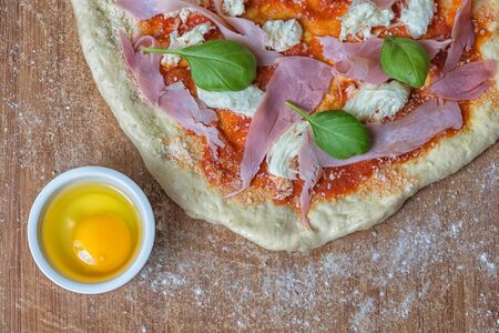 Pizza prosciutto cotto mozzarella egg raw cupの写真素材