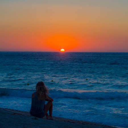 Lefkada Greece sunset observed by silhouetted woman standing at watersの写真素材