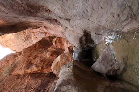 The water of the little stream in the Wadi Ghuweir canyon, running over colorful stones, Dana, Jordan 2021の写真素材