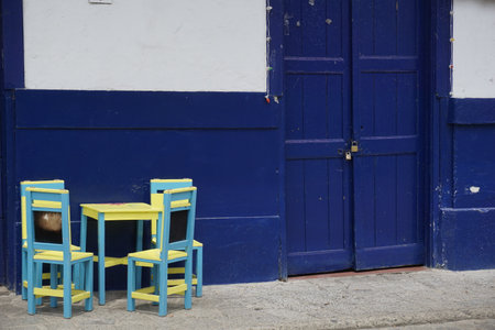 Little wooden chairs and table in front of a blue house, blue facade in Jardin, Eje Cafetero, Colombia 2020の写真素材