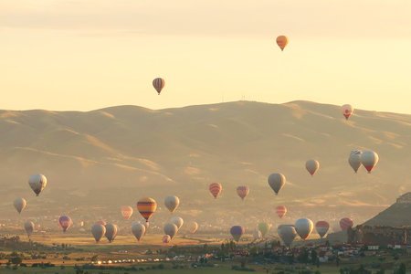 Many colorful hot air balloons over the landscape of the Red Valley, Rose Valley all about to land next to Cavusin after sunrise, Cappadocia, Turkey 2022の写真素材