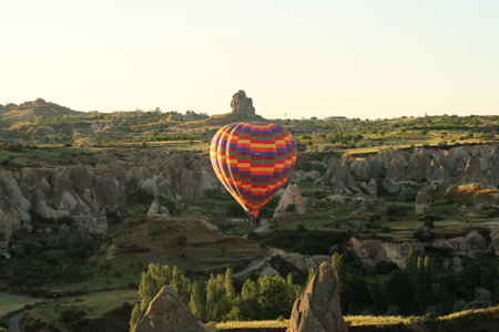 Colorful hot air balloon flying over the landscape of Cappadocia with its famous fairy chimneys, close to Gの写真素材
