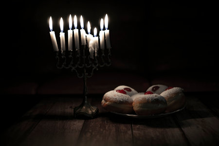 hanukkah candle on wooden background with donutsの写真素材