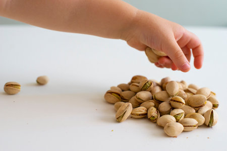 Pistachio nuts in the hands of a child on a white backgroundの写真素材