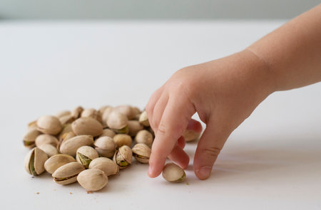 Pistachio nuts in a child's hand on a white backgroundの写真素材