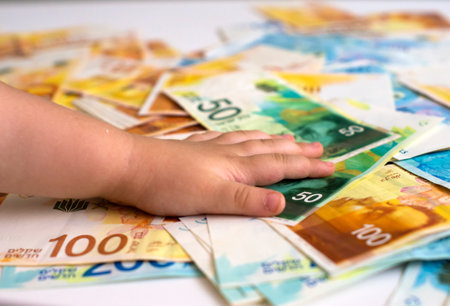 Child's hand taking money from a pile of euro banknotes.の写真素材